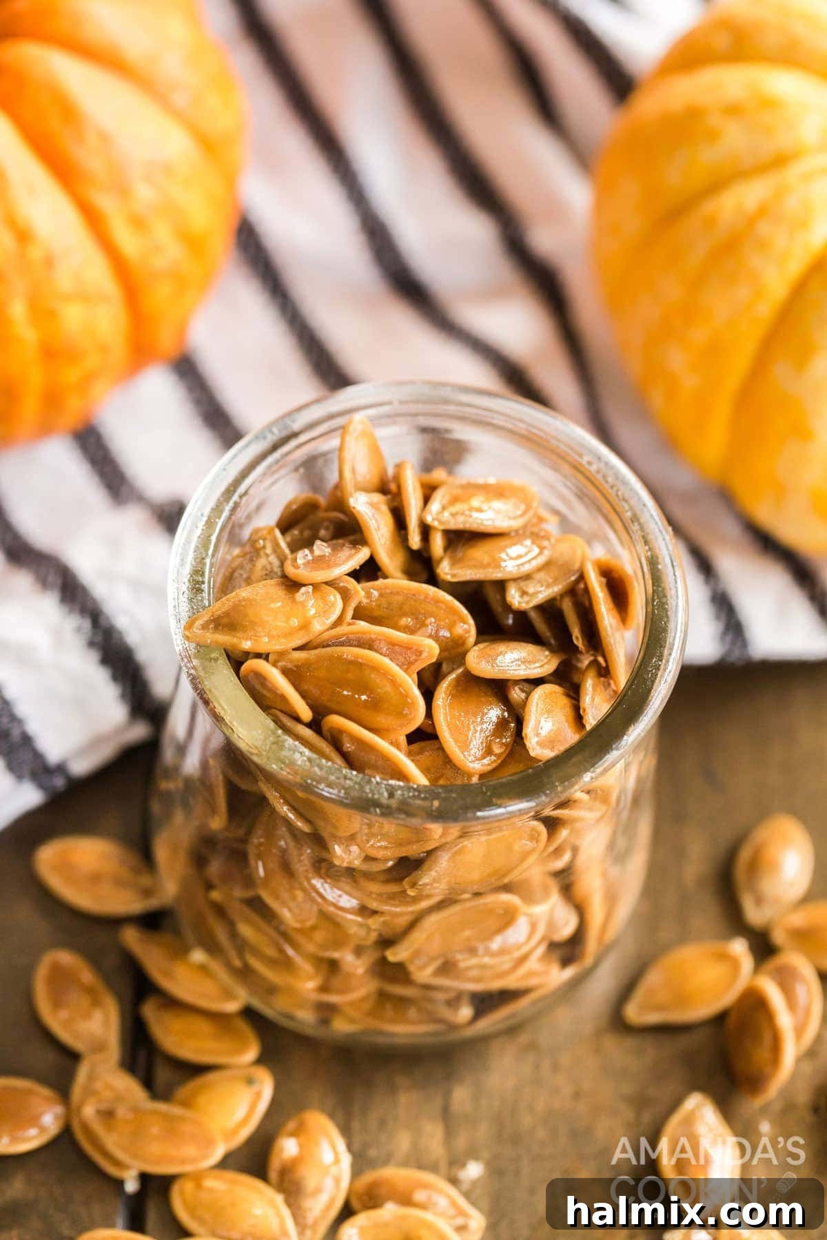 A glass jar filled with roasted pumpkin seeds, garnished with whole pumpkin seeds, a perfect autumnal display.