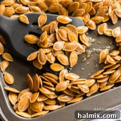 Cookie sheet of roasted pumpkin seeds and spatula, capturing the essence of a warm, homemade snack.