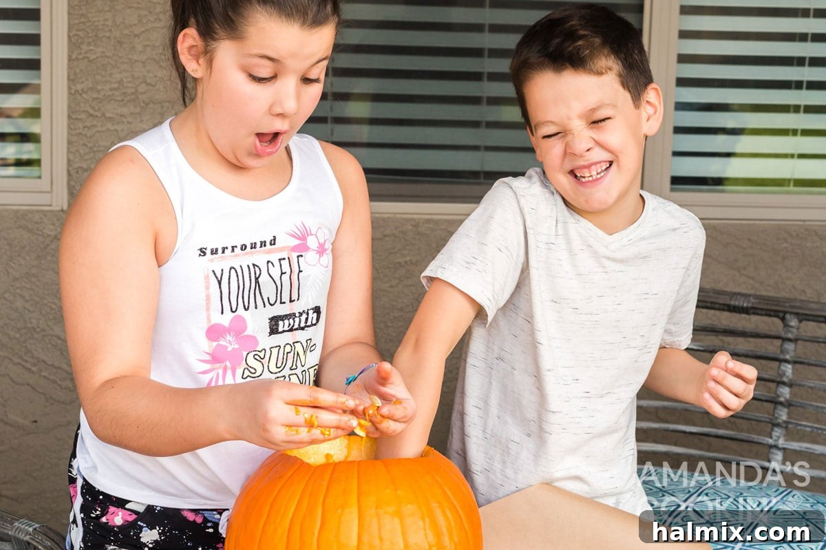 Kids actively engaged in cleaning out a pumpkin, scooping out the seeds and pulp.
