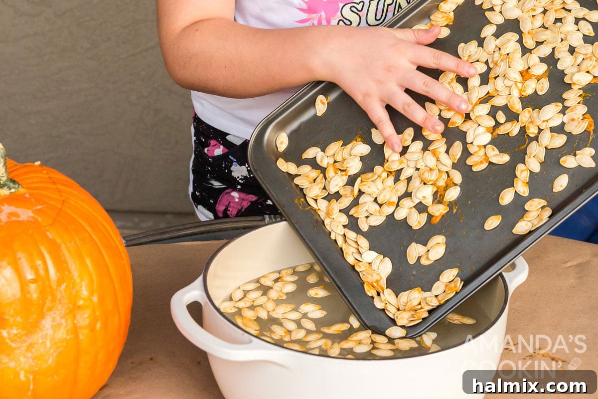 A child carefully adding pumpkin seeds and pulp into a pot of water for cleaning.