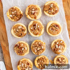 Pecan Tassies on a wooden cookie board, showing their golden crust and rich filling.