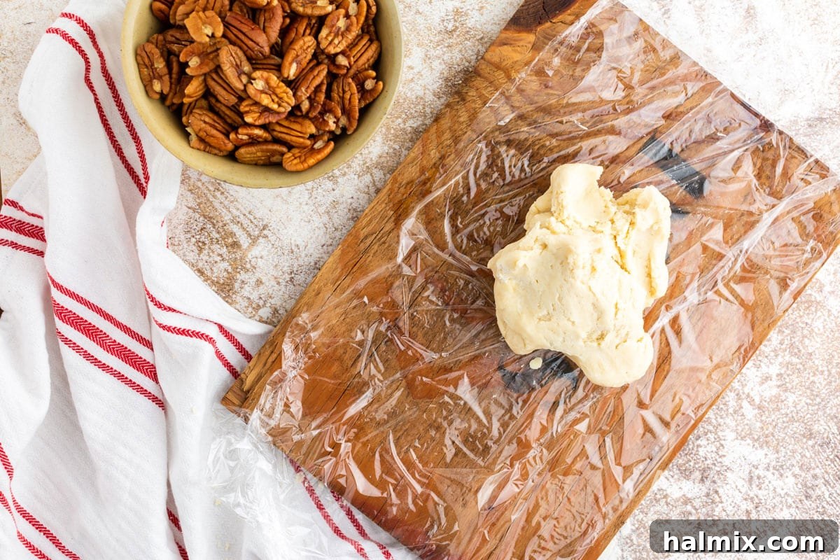 Cookie dough log wrapped in plastic wrap, ready for chilling in the refrigerator.