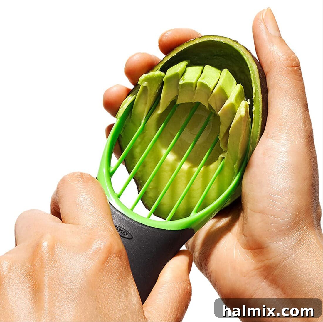 21 Clever Kitchen Gadgets You'll Use Constantly 5 A hand using an avocado slicer to perfectly slice a ripe avocado, illustrating its multi-functionality.