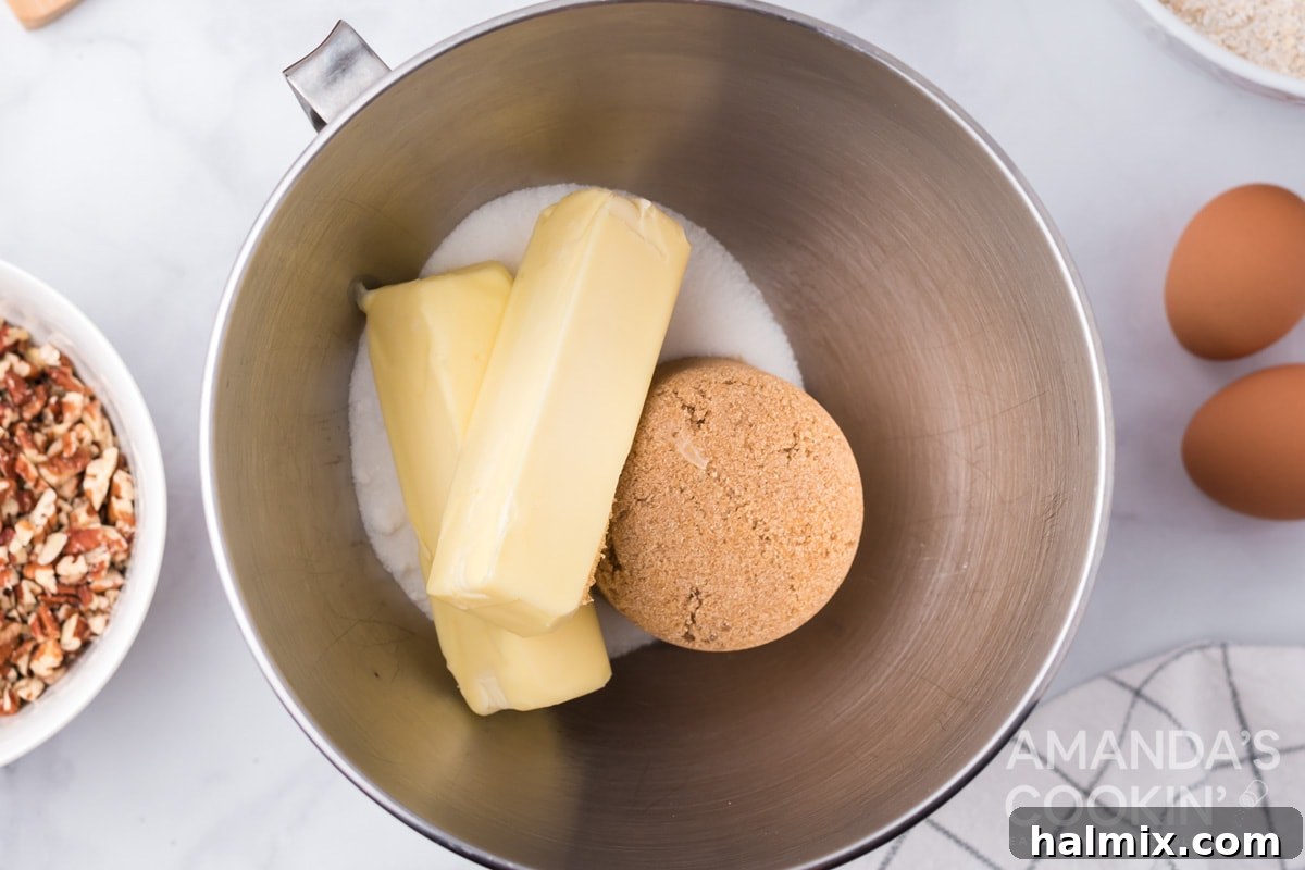 Softened butter and two types of sugar being creamed together in a mixing bowl with an electric mixer.