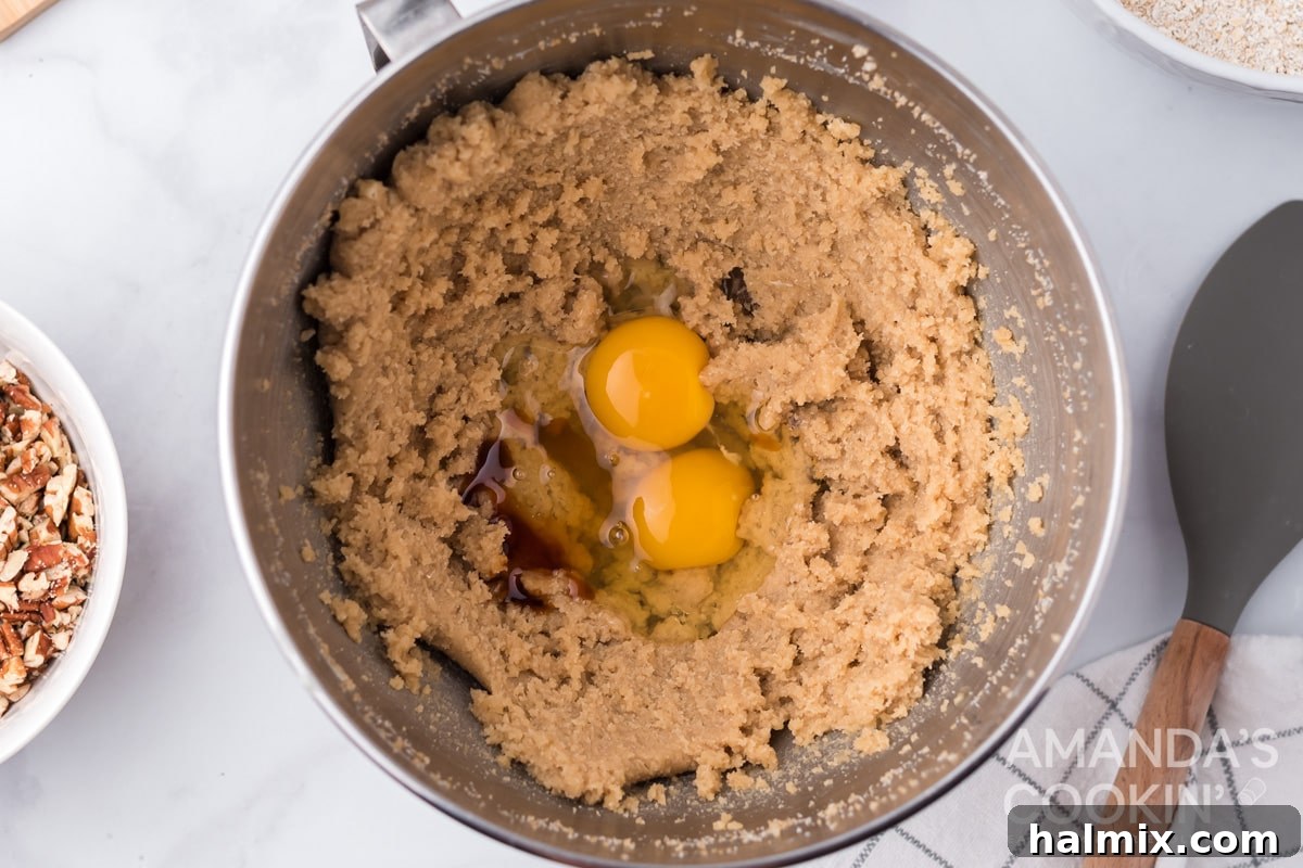 Eggs and vanilla extract being beaten into the creamy butter and sugar mixture.