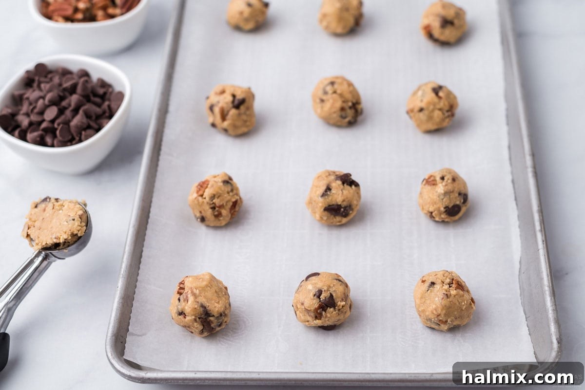 Raw cookie dough balls placed on a parchment-lined baking sheet, ready for the oven.
