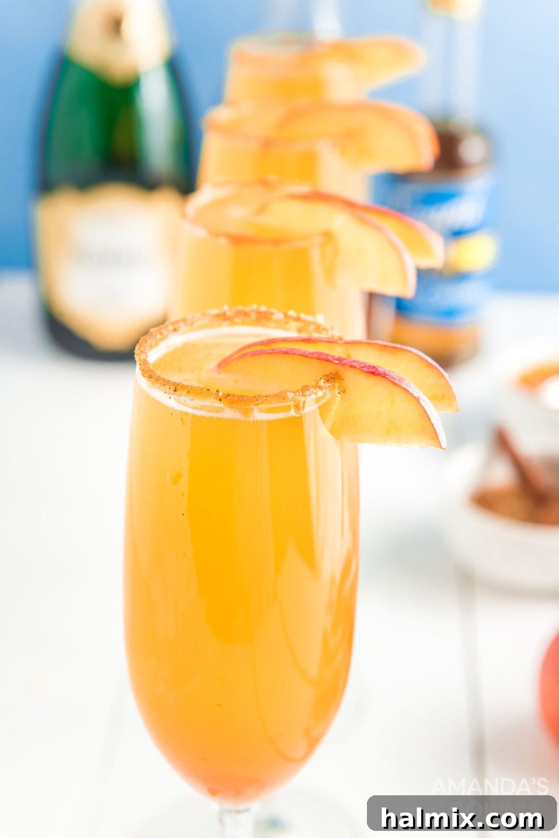 Close-up of caramel mimosas garnished with apple slices, showcasing the caramel and cinnamon sugar rim.