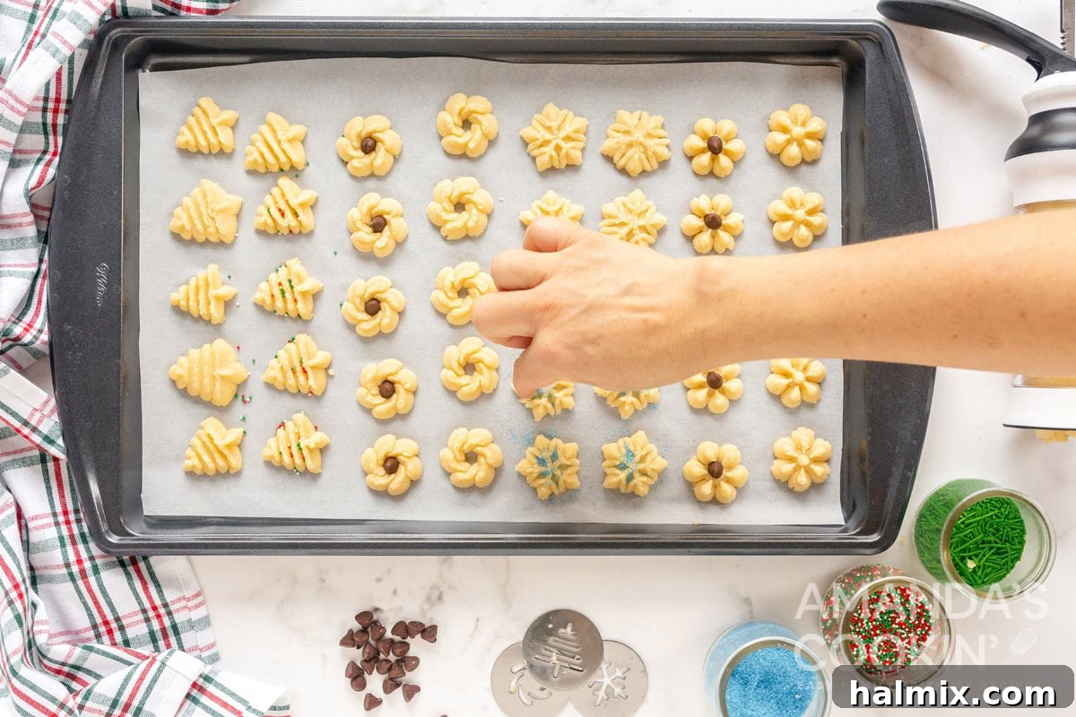 hand adding colored sugar to unbaked spritz cookies