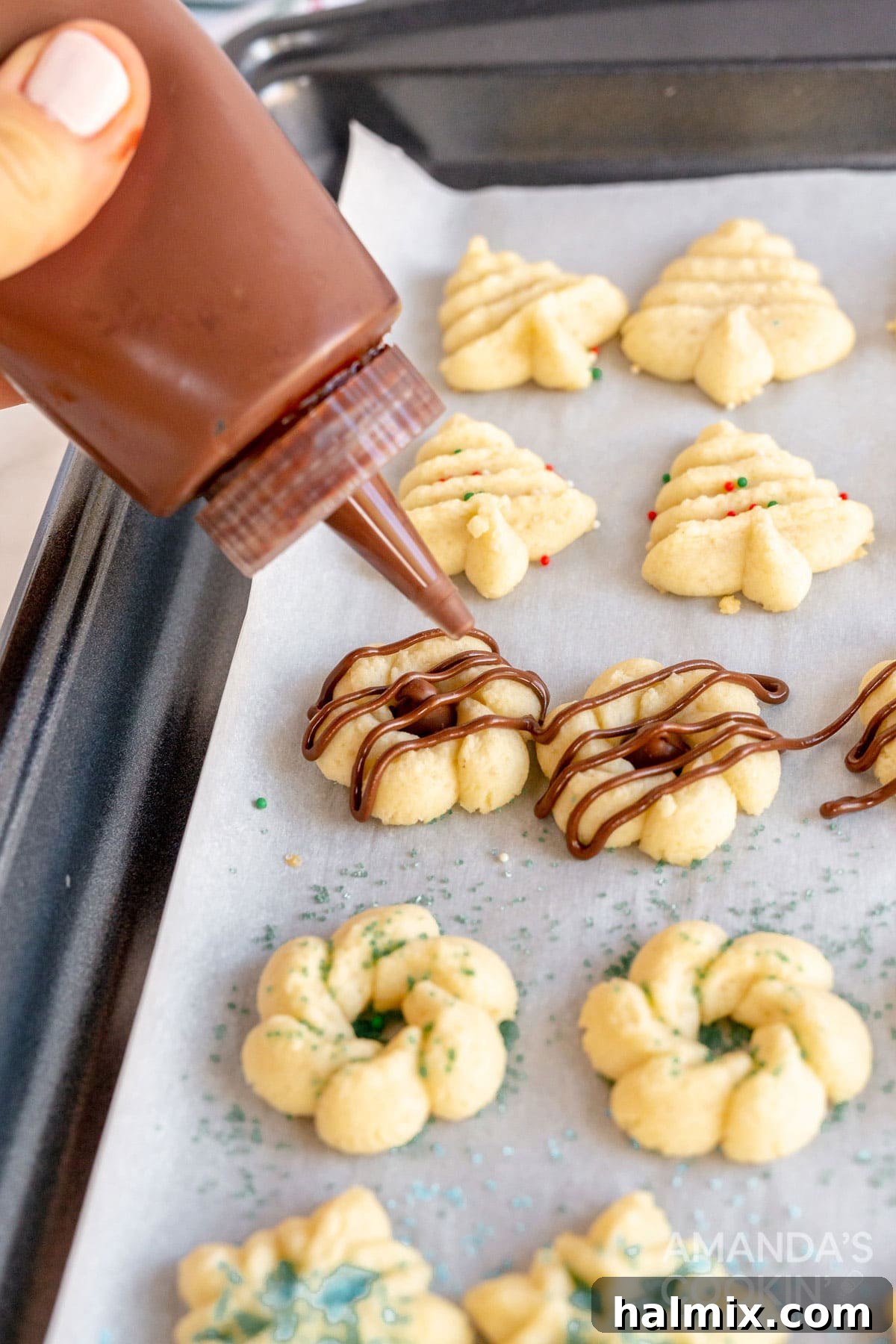 melted chocolate being drizzled artistically over a plate of spritz cookies