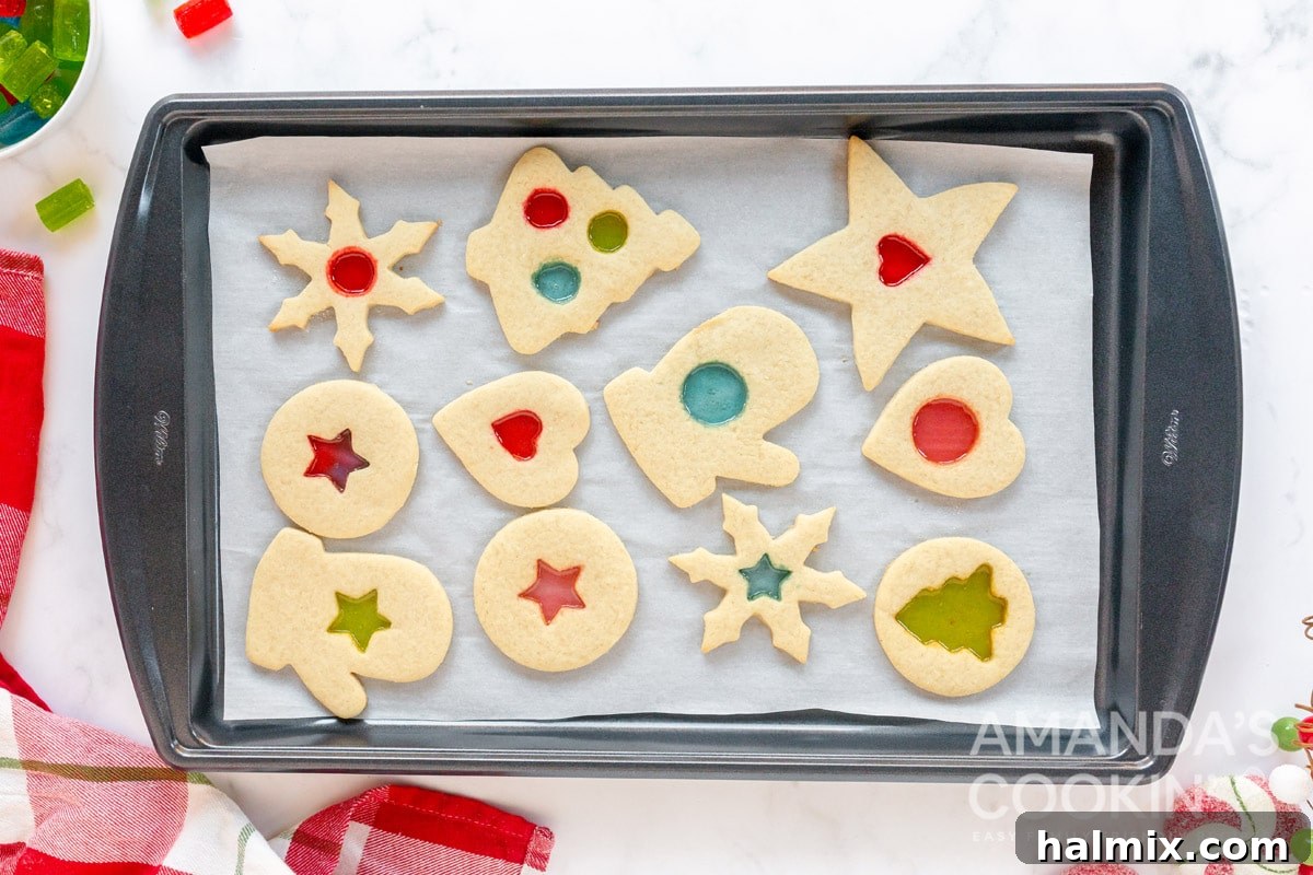 A baking sheet filled with freshly baked stained glass cookies, with perfectly melted and colorful candy centers, cooling down.