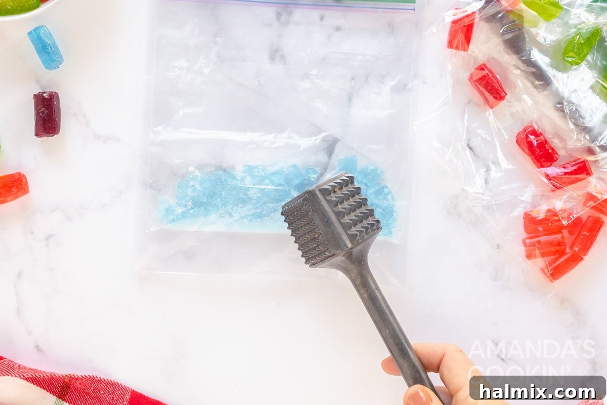 Hands crushing colorful hard candies in a plastic bag with a rolling pin.