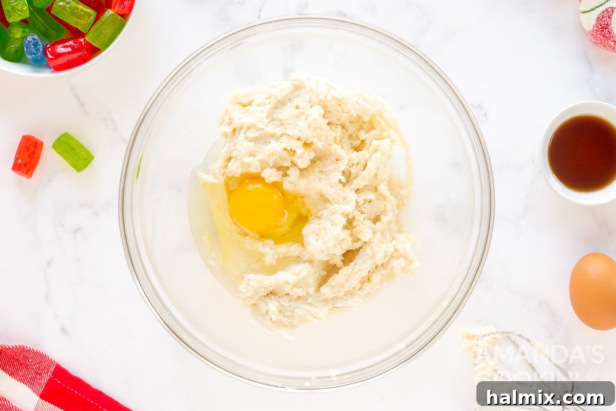 Two eggs cracked into a bowl with creamy butter and sugar mixture, ready to be combined.