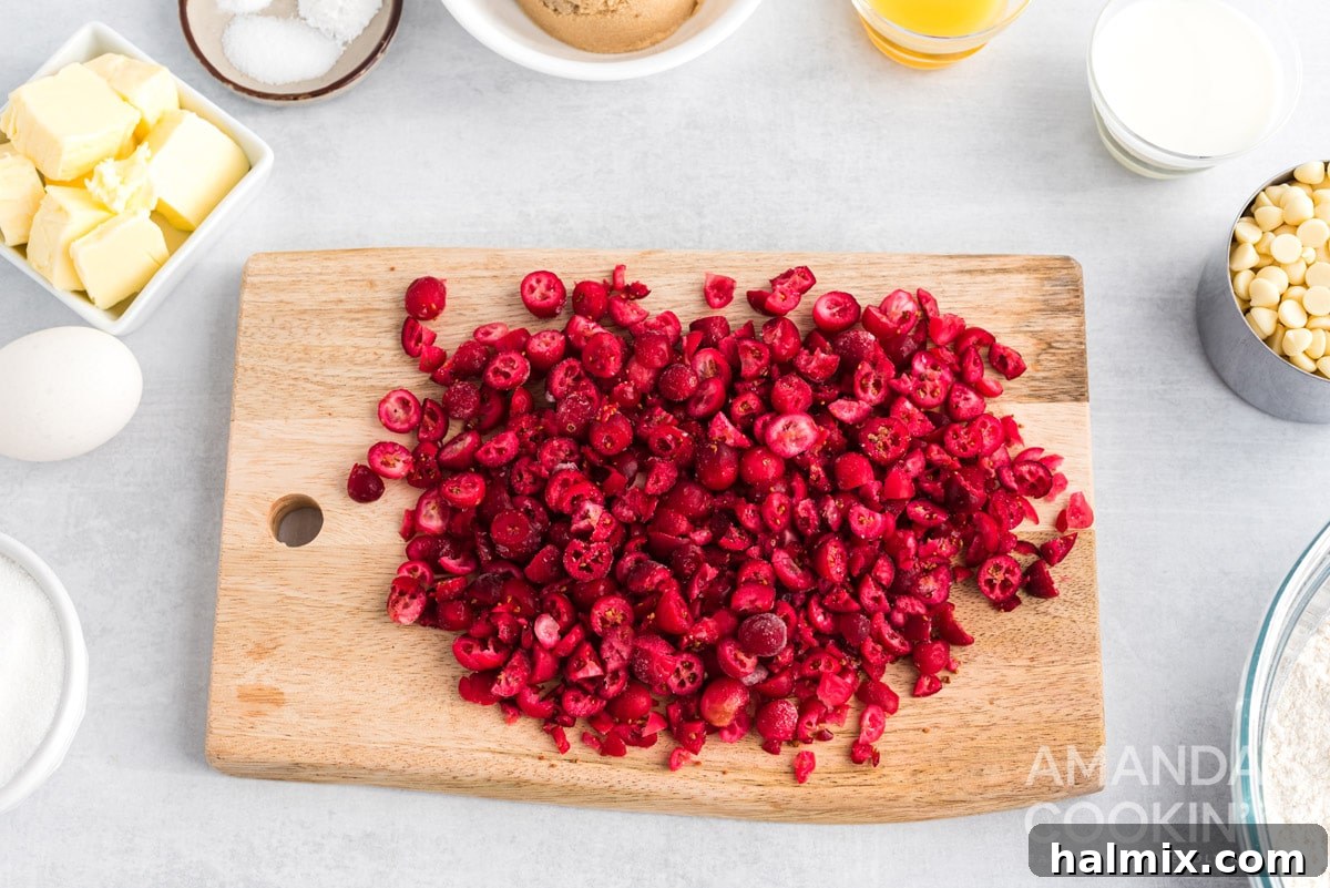 Chopped frozen cranberries on a cutting board, ready for the freezer.