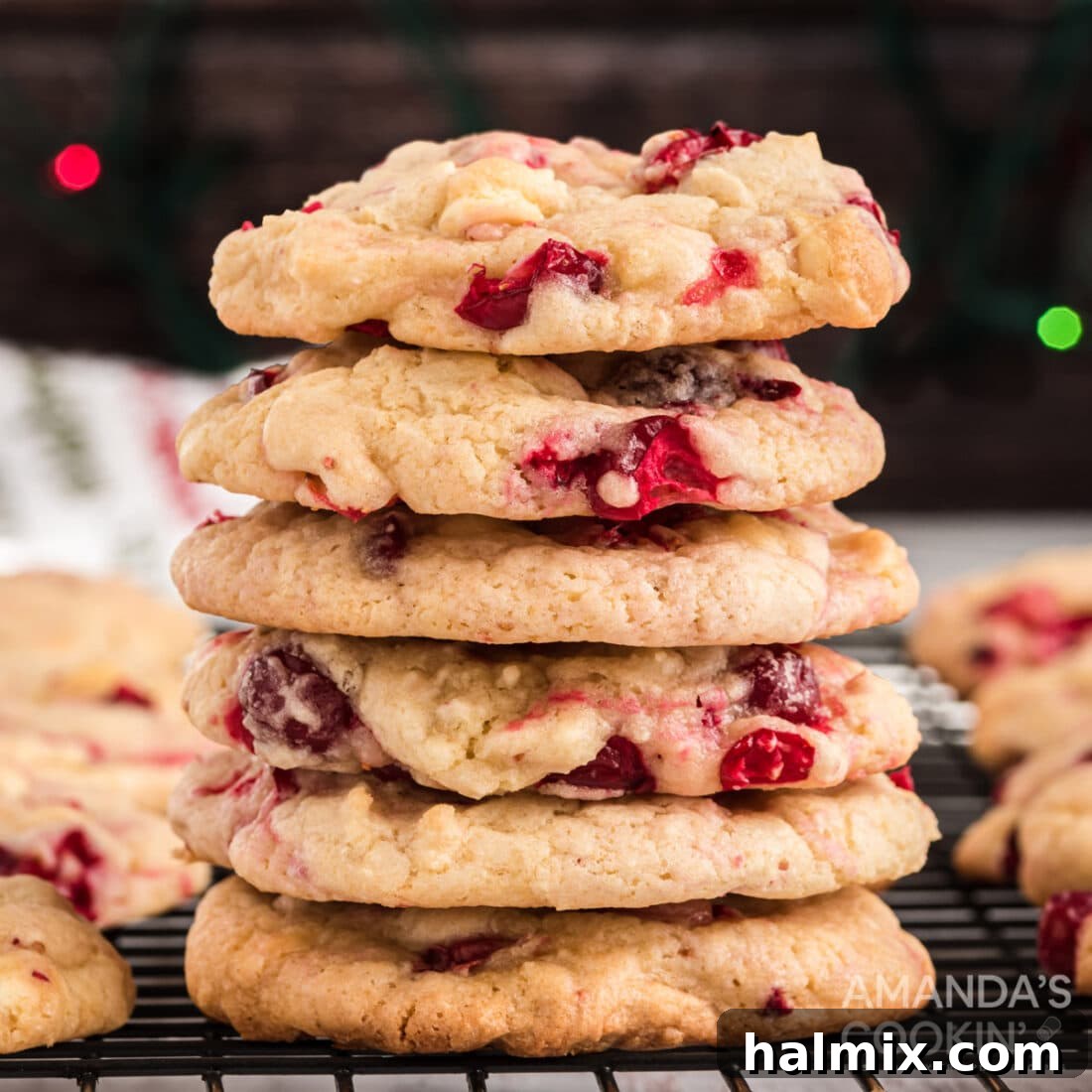 A delectable stack of golden white chocolate cranberry cookies, beautifully flecked with bright red cranberries, presented on a festive plate.
