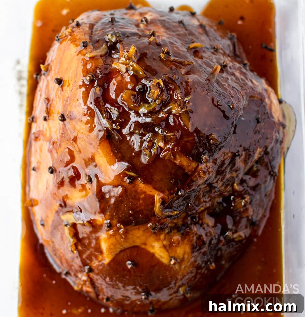 Glazed ham baking in the oven, with juices pooling at the bottom of the pan
