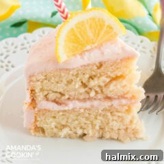 slice of pink lemonade cake with a slice of lemon on top