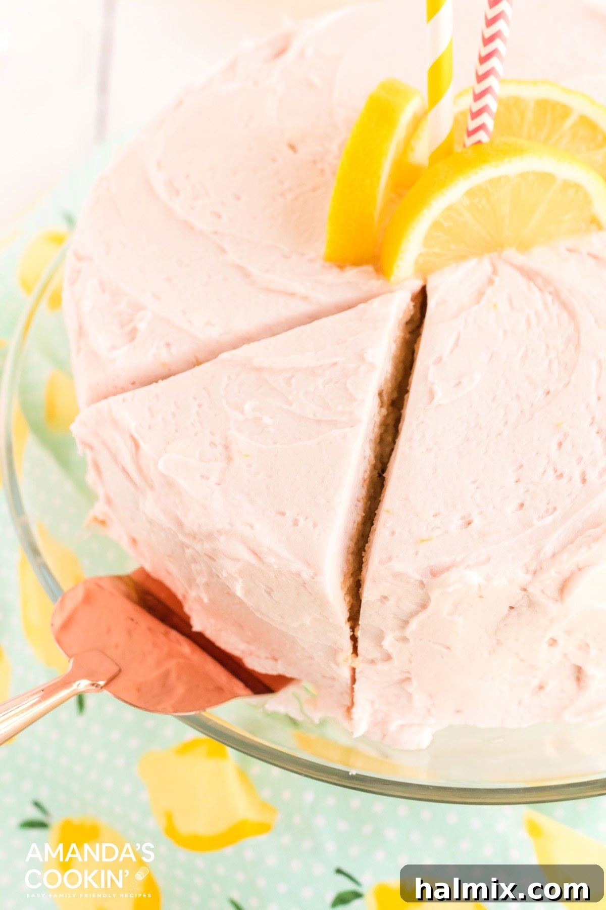 A slice being carefully removed from a round pink lemonade cake with a pie server