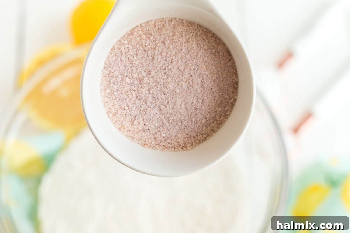 Adding pink lemonade powder to a bowl of dry ingredients