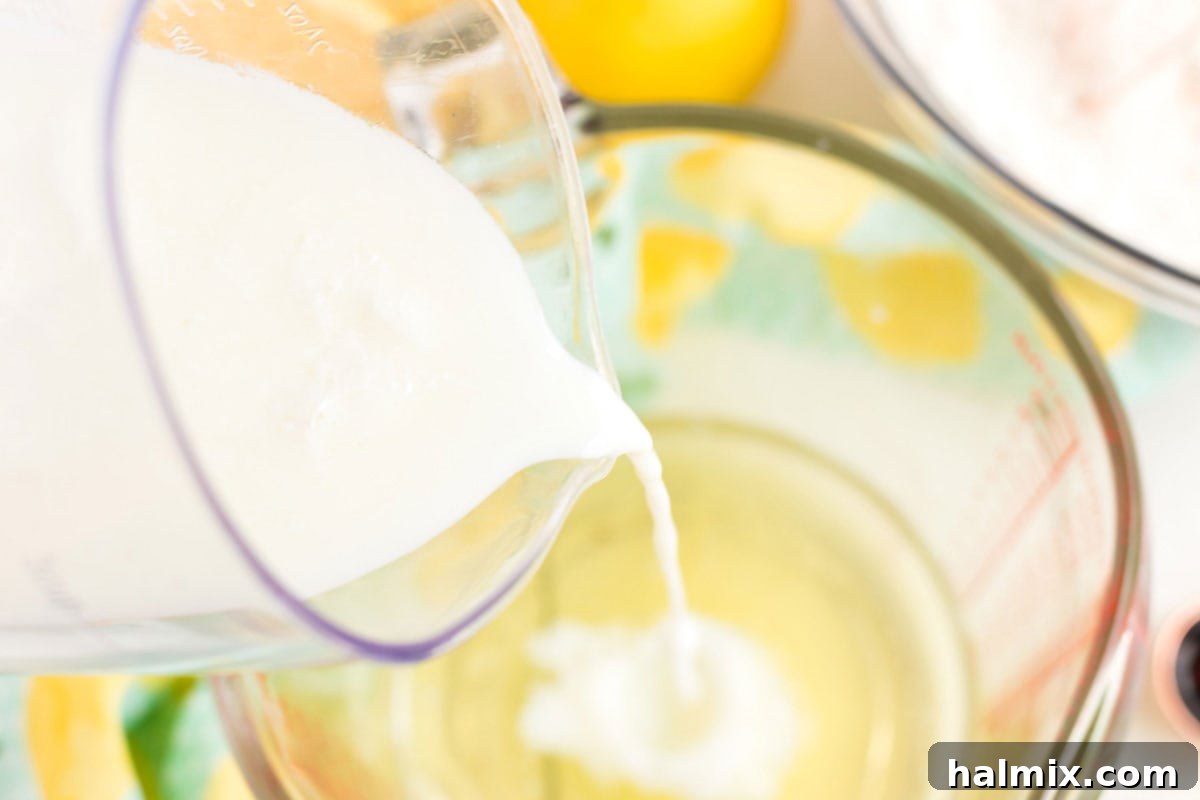 Adding buttermilk to a bowl with egg whites and vanilla