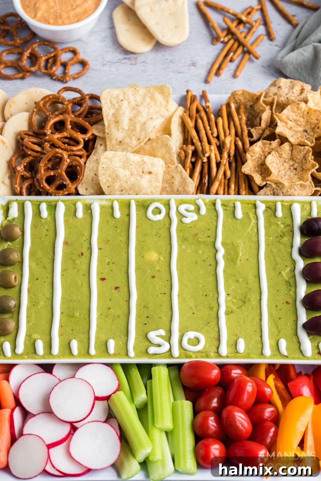 Vibrant football party tray featuring fresh guacamole, an assortment of colorful vegetables, and crispy crackers, perfectly arranged for game day.