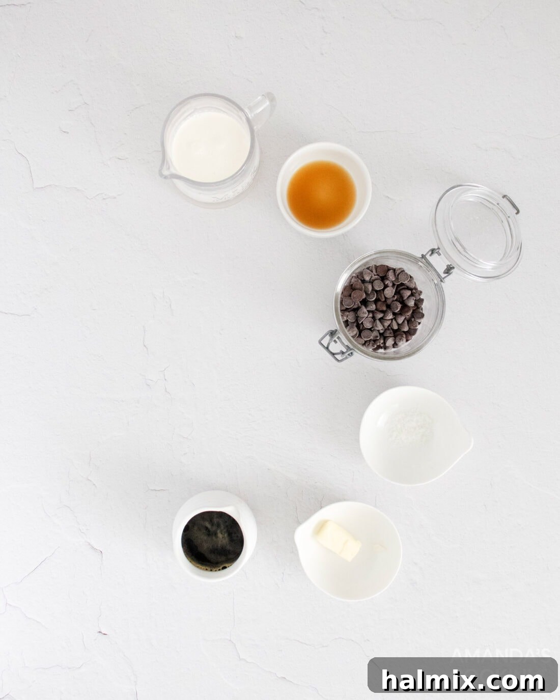 A flat lay photograph showcasing all the ingredients required for making mocha truffles: heavy cream, semi-sweet chocolate, espresso, butter, vanilla extract, and sea salt.