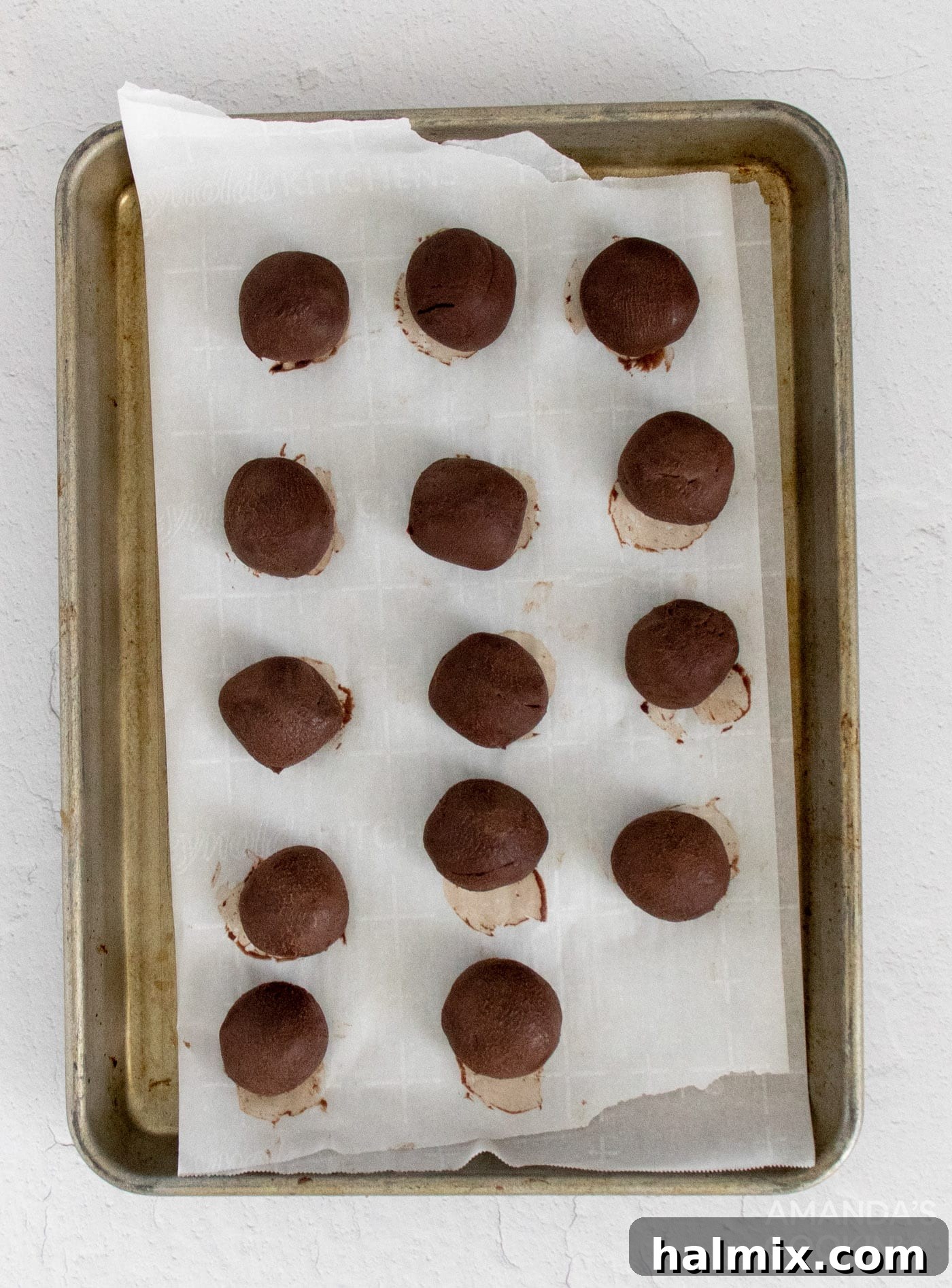 Numerous perfectly scooped and rolled mocha truffles neatly arranged on a parchment-lined baking pan, ready for their final chill before coating.