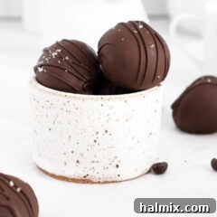A top-down view of perfectly round mocha truffles, glistening with a smooth chocolate coating, with some light drizzles of chocolate as decoration.