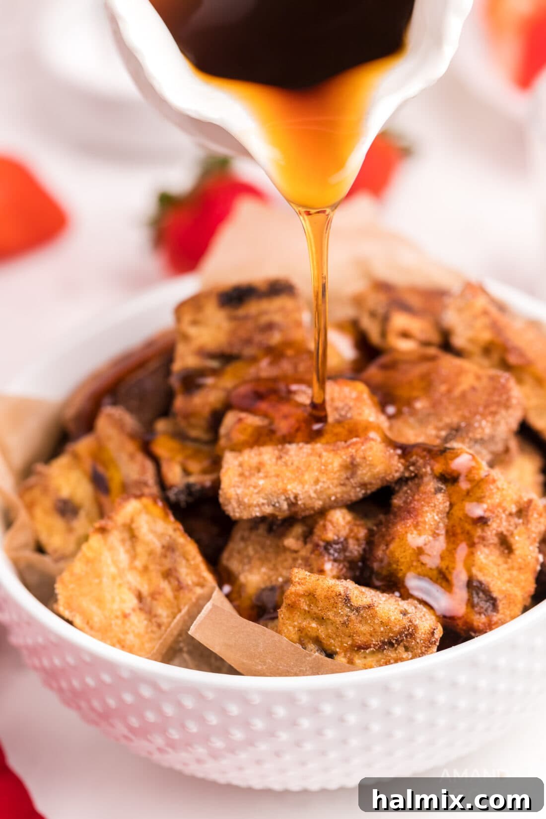 Air Fryer French Toast Poppers 11 A generous pour of golden maple syrup cascading over a plate of freshly made Air Fryer French Toast Bites.