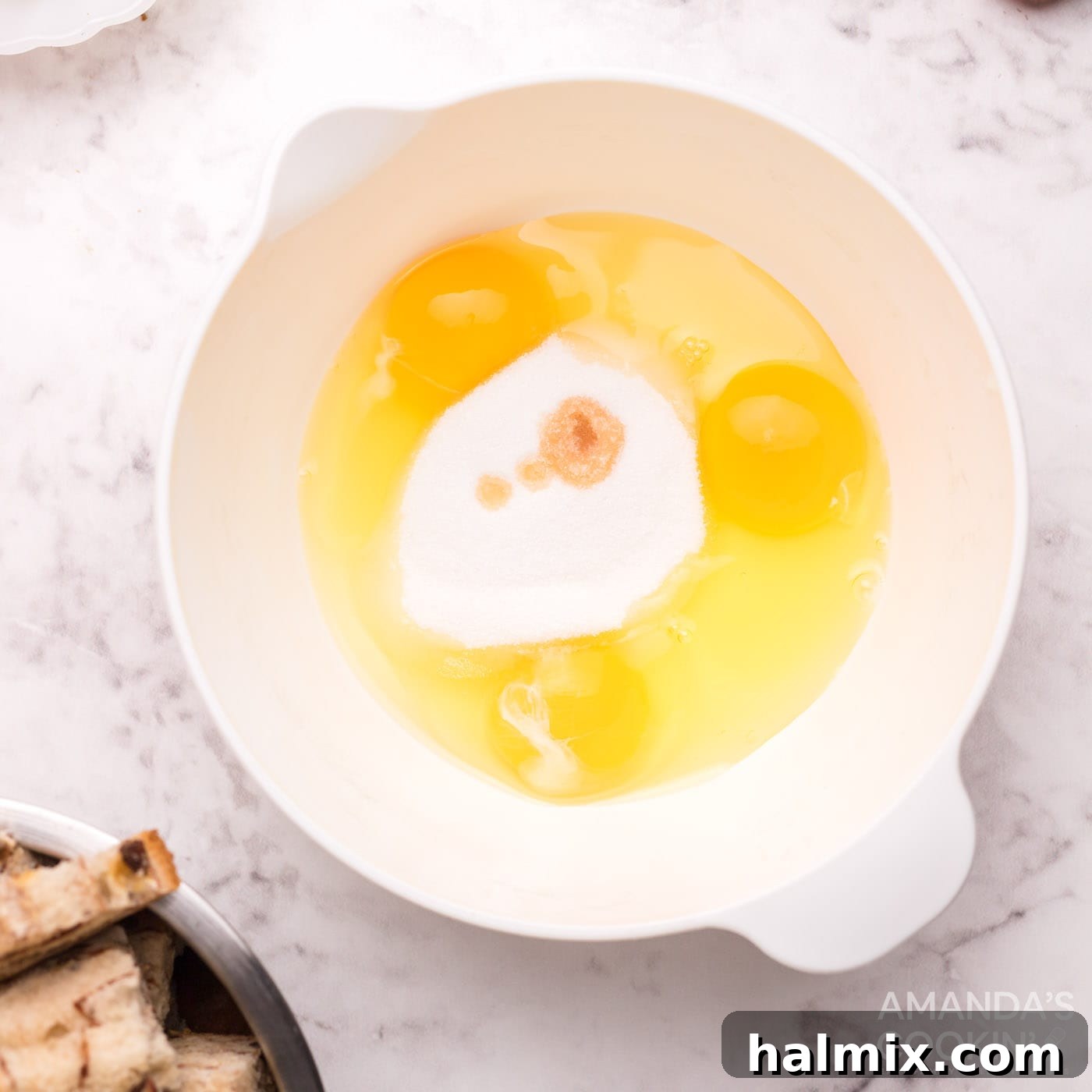 A bowl filled with whisked eggs, buttermilk, sugar, and maple extract, forming the delicious French toast batter.