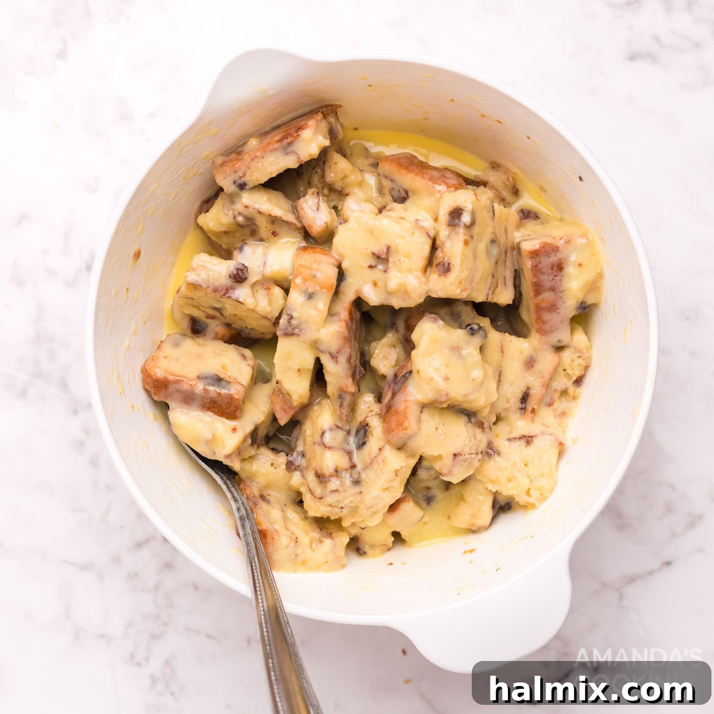 Bread squares soaking in a bowl of creamy egg mixture, ensuring each piece is fully coated for optimal flavor.