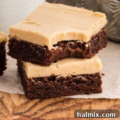 Two brownies, one with a delightful bite out of it, showcasing the layers of fudge and peanut butter frosting.