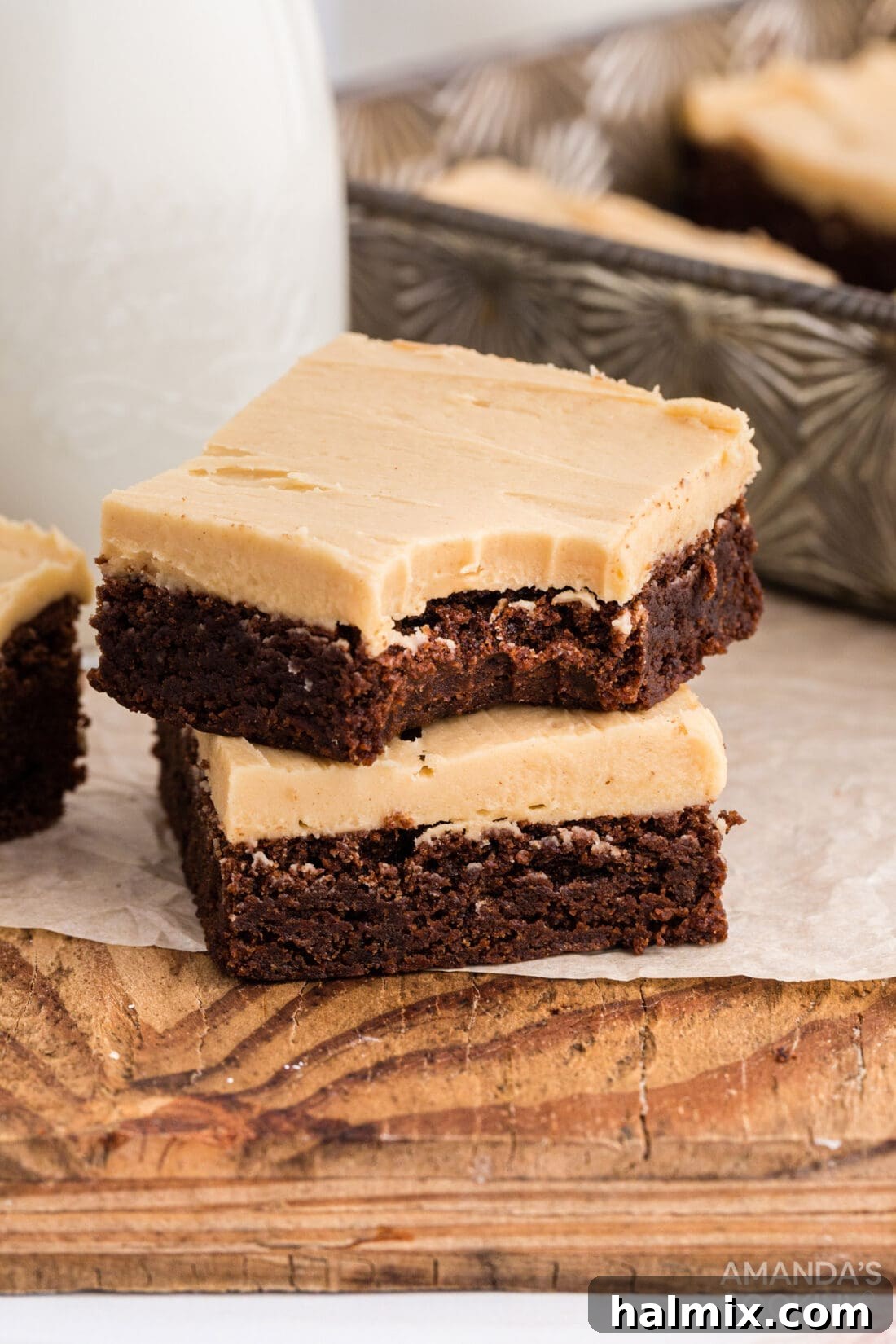 Two fudgy brownies, one with a delectable bite taken out, showcasing the rich chocolate and creamy peanut butter frosting layers.