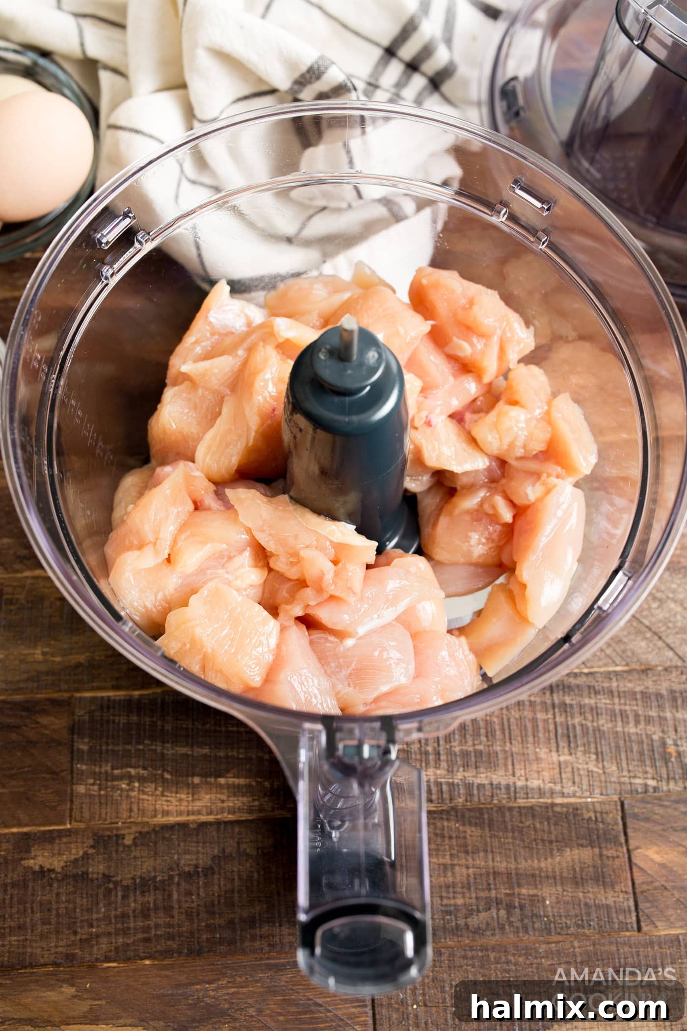 Cubed chicken breast pieces ready to be processed in a food processor, showing the initial stage of making the chicken paste.
