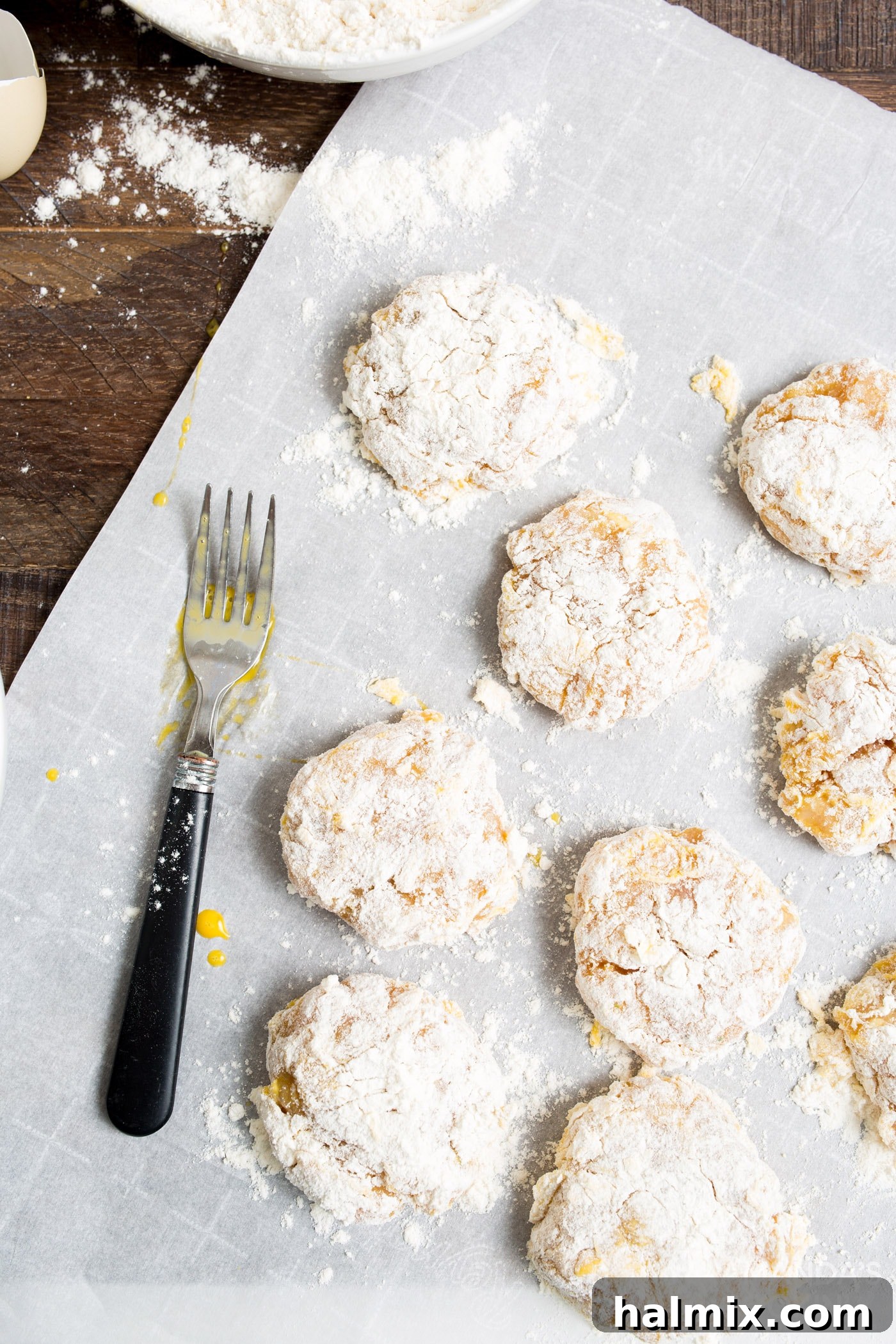 Four perfectly breaded raw chicken nuggets laid out on parchment paper, showcasing the double coating before air frying.