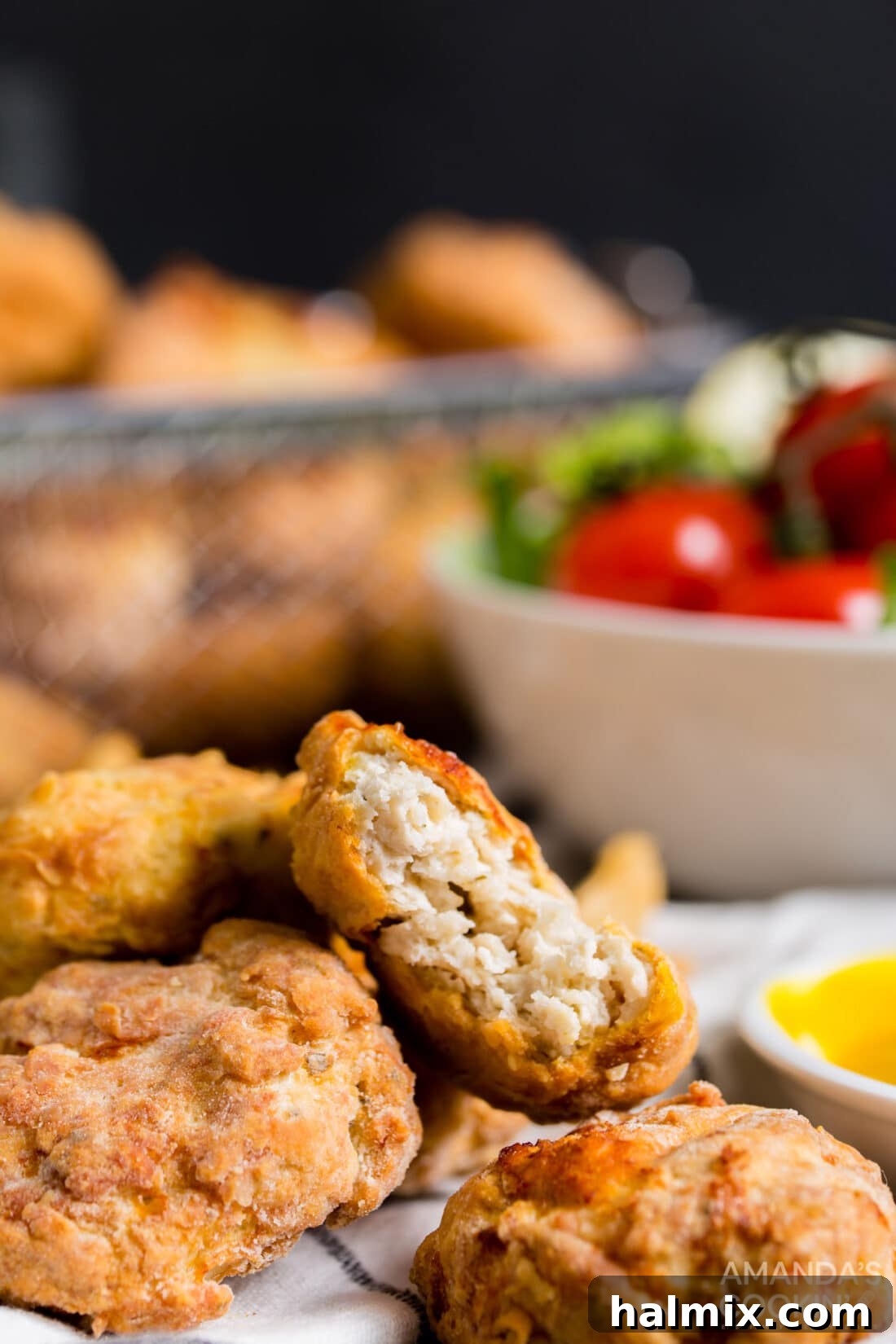 A close-up of a perfectly cooked air fryer chicken nugget with a bite taken out, revealing the tender white meat inside and the crispy coating.
