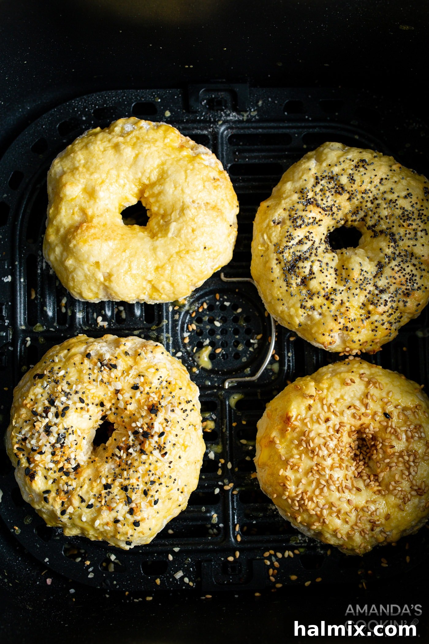 Partially cooked air fryer bagels being brushed with egg wash before adding desired toppings.
