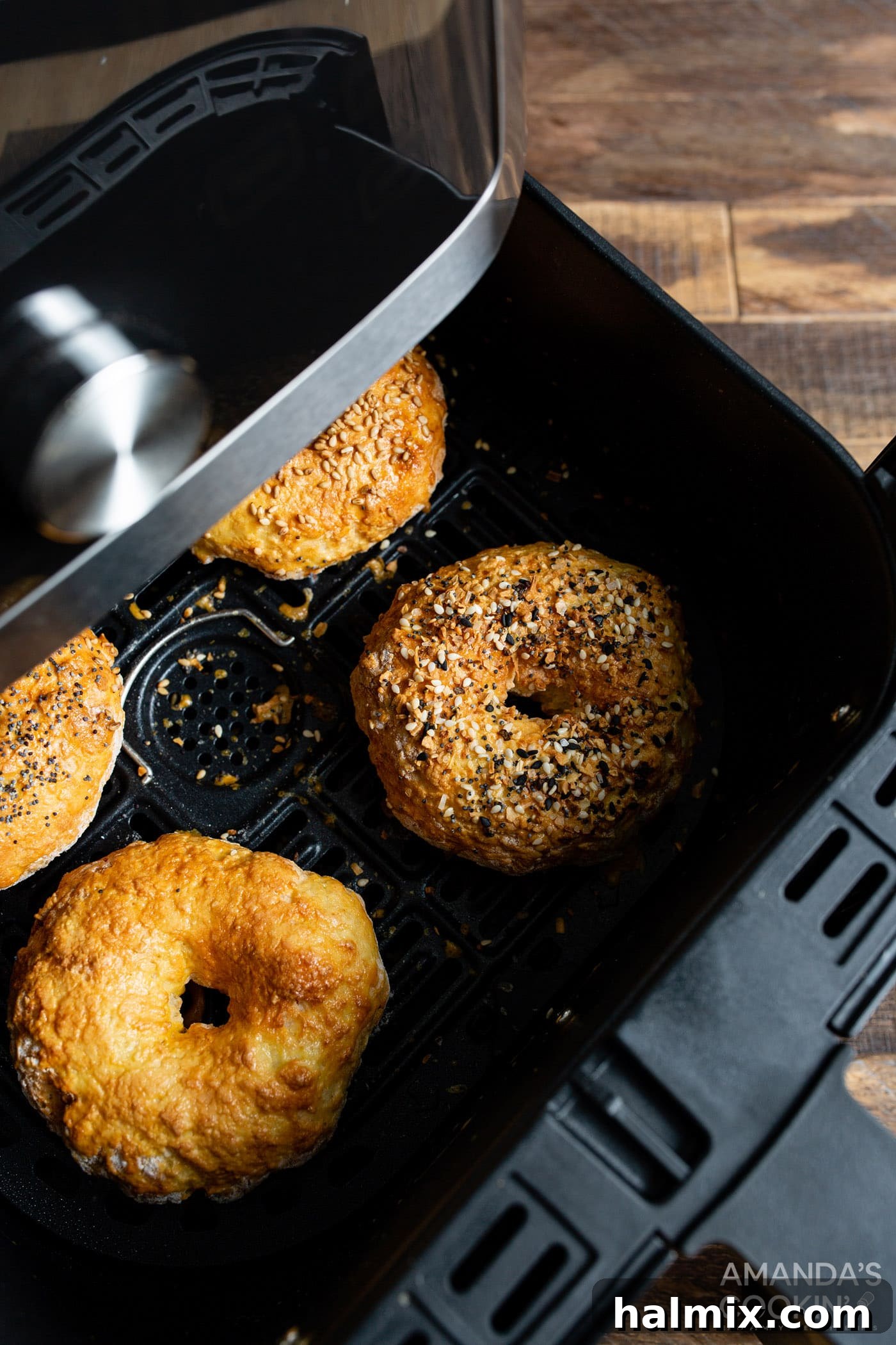 Finished golden brown air fryer bagels resting inside the air fryer basket after completion.
