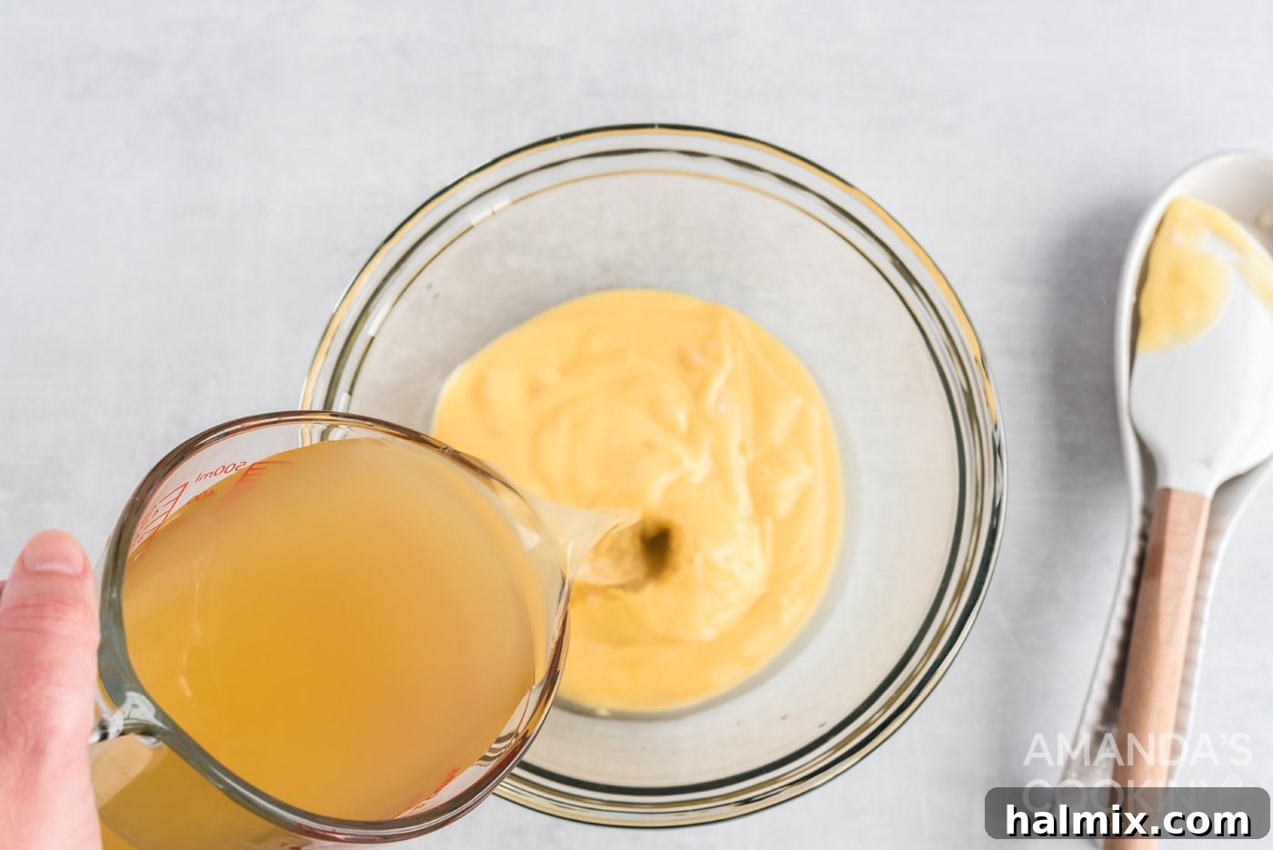 Adding chicken broth to a bowl containing condensed cream of chicken soup.