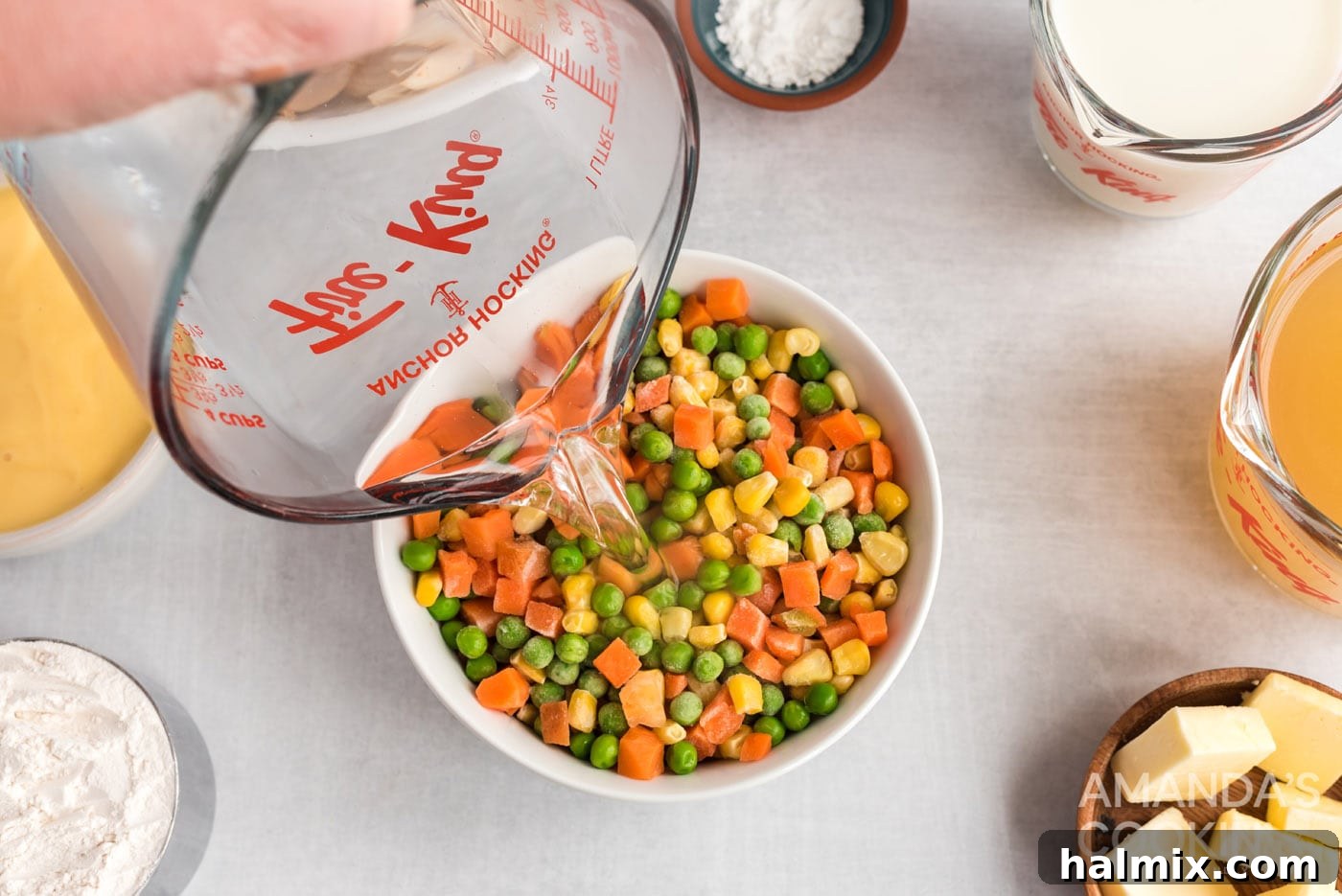 Pouring hot water over frozen mixed vegetables in a bowl.