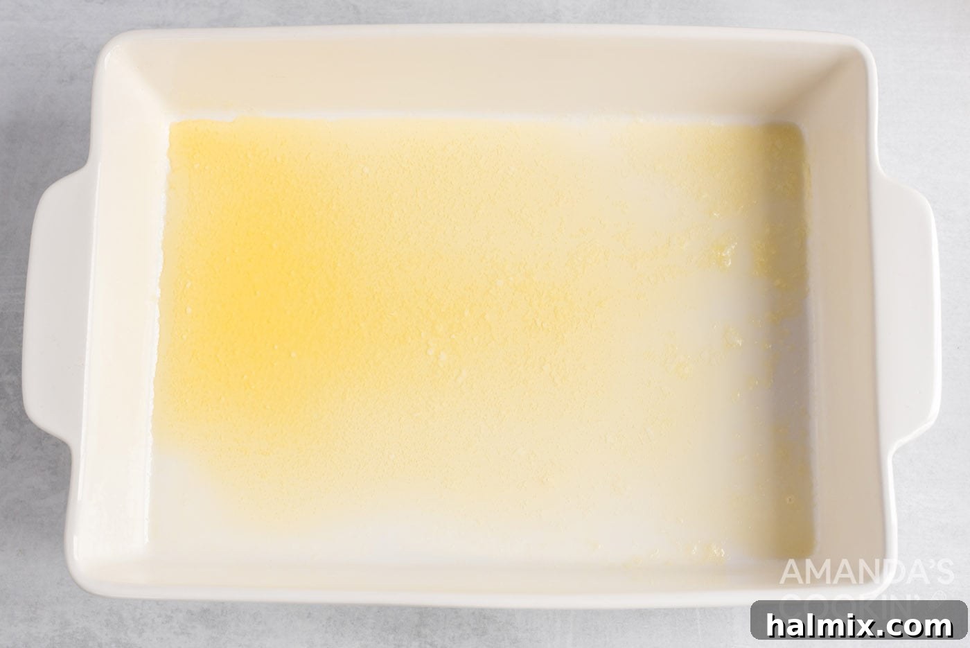 Melted butter shimmering in the bottom of a glass baking dish.