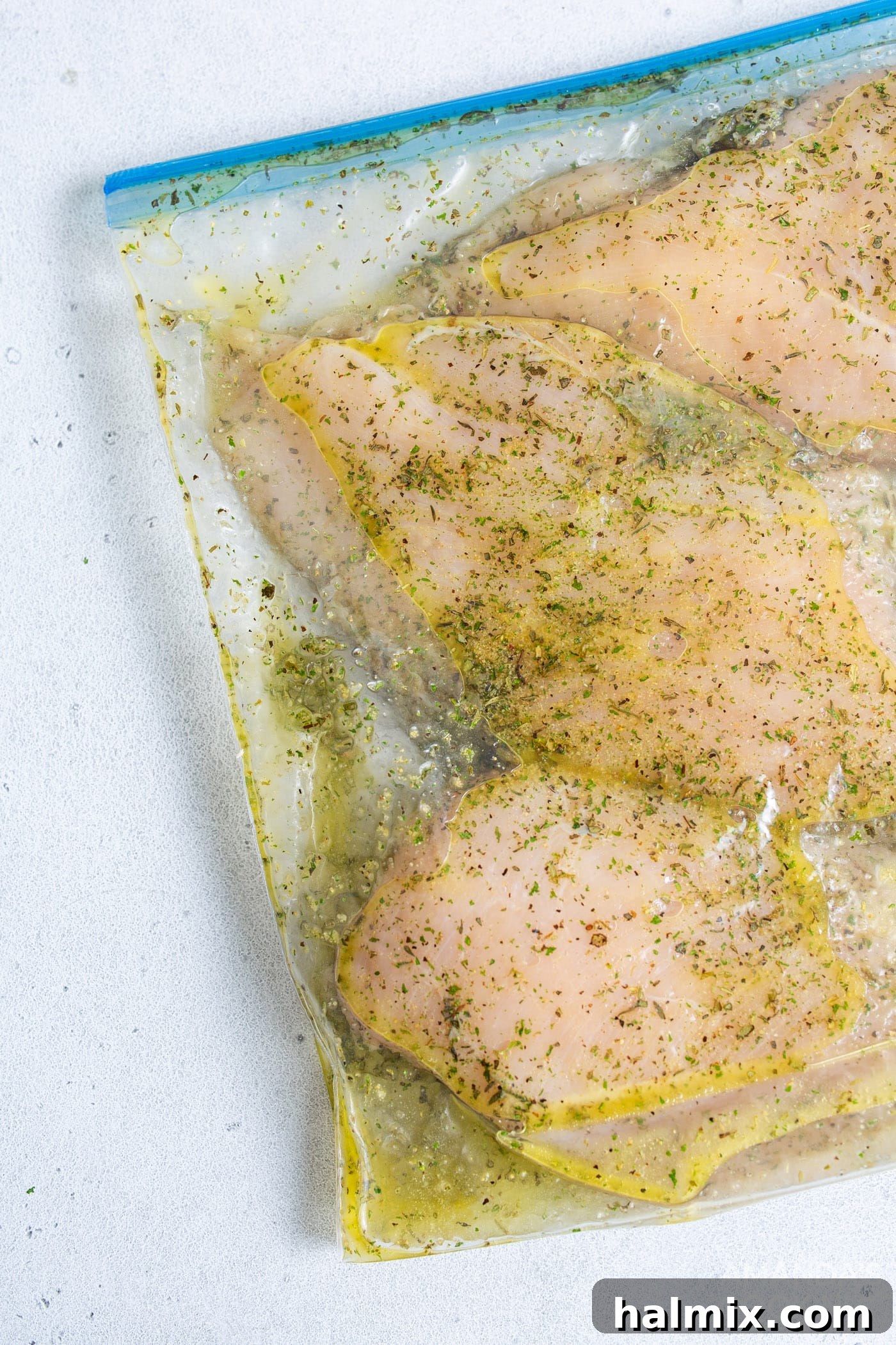 Chicken breasts being seasoned in a plastic bag