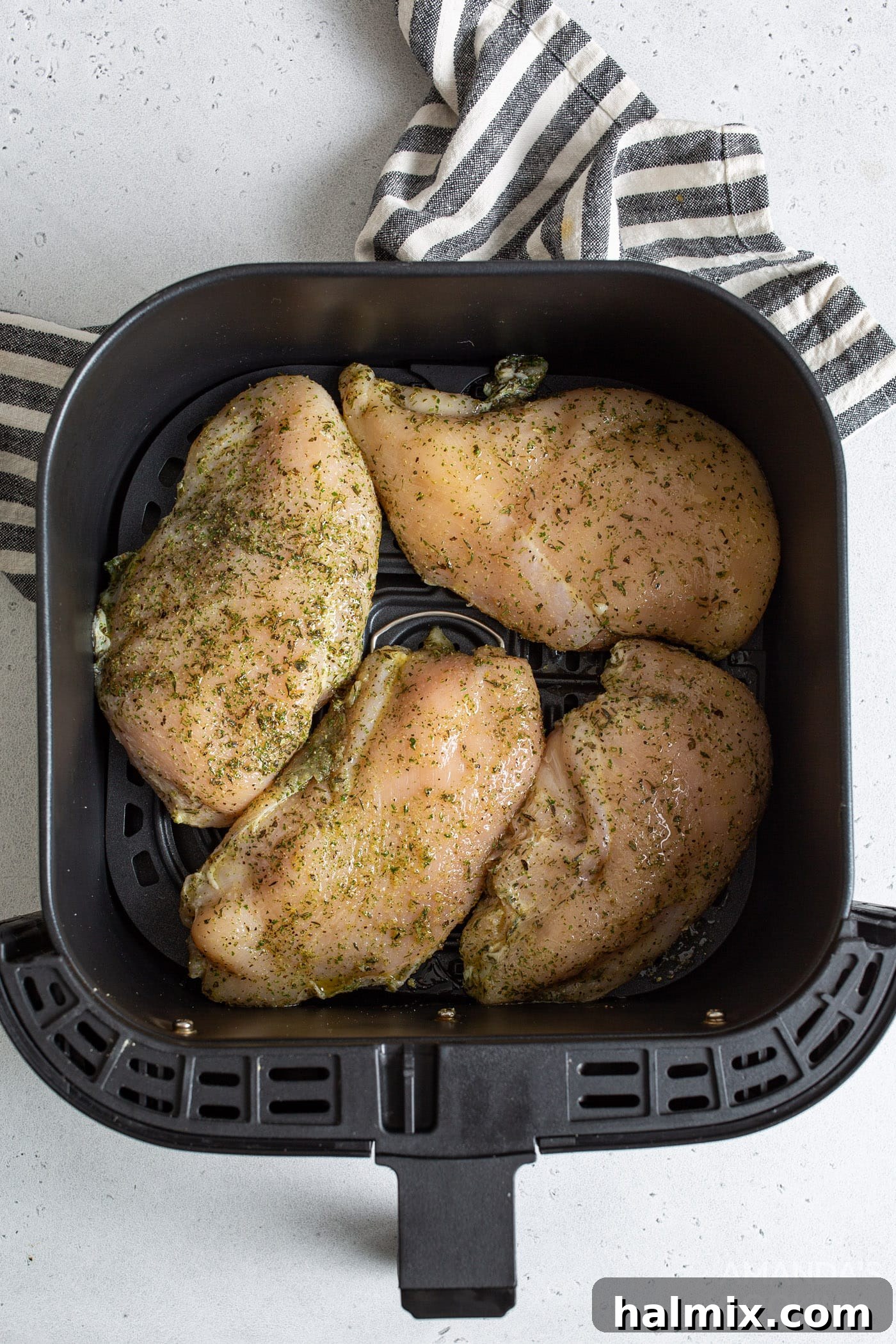 Raw chicken breasts arranged in air fryer basket before cooking