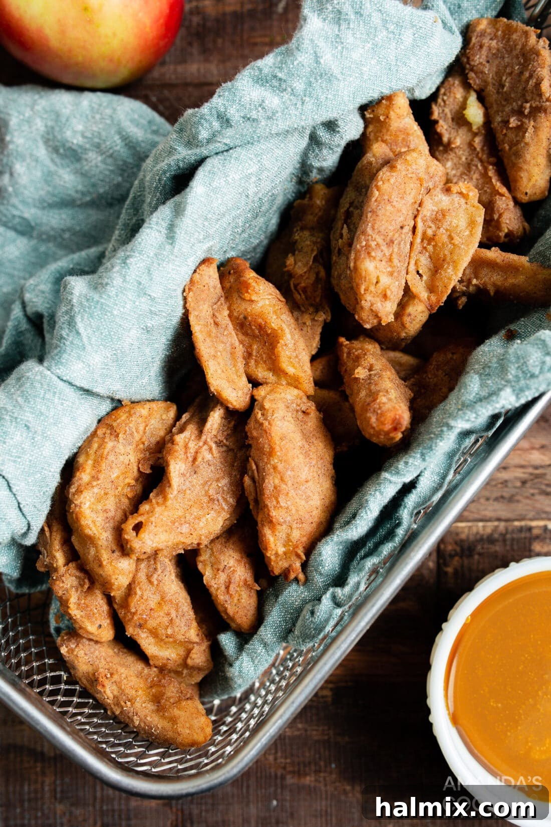 Golden brown air fryer apple fries piled in an air fryer basket, ready to be served.