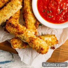Golden air fryer mozzarella sticks served with marinara sauce in a rustic setting.