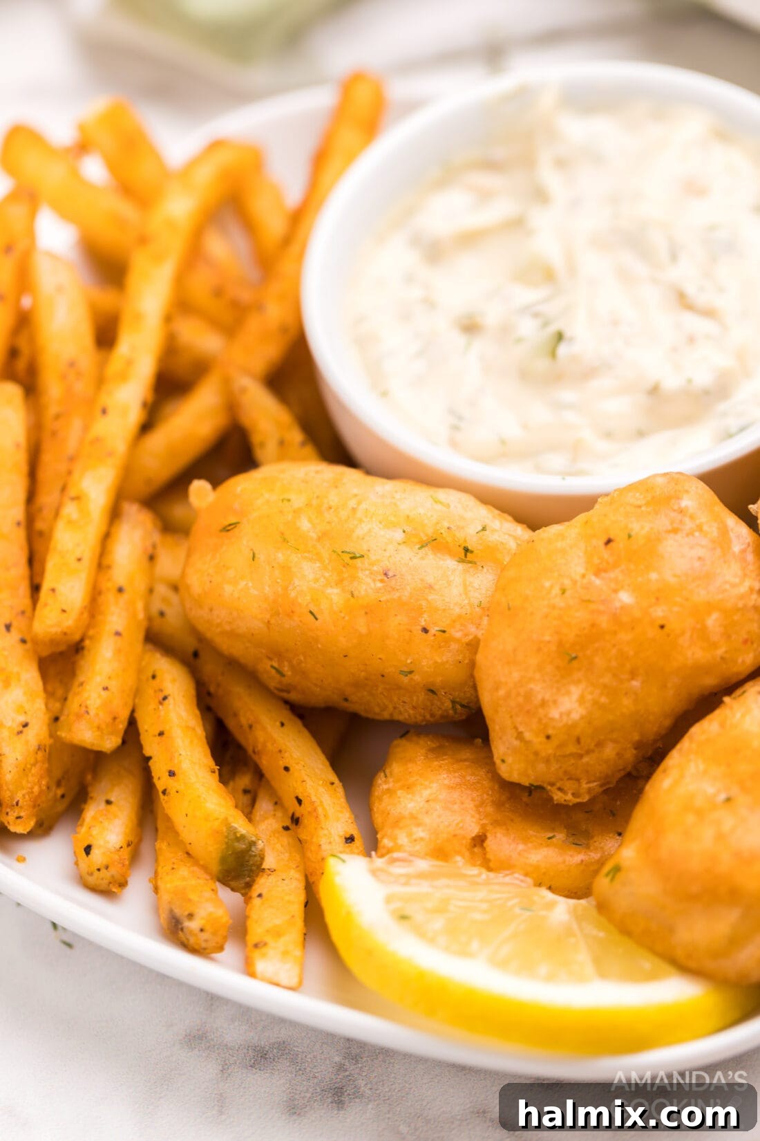 Golden-brown beer battered fish and chips served on a plate with fresh lemon wedges.