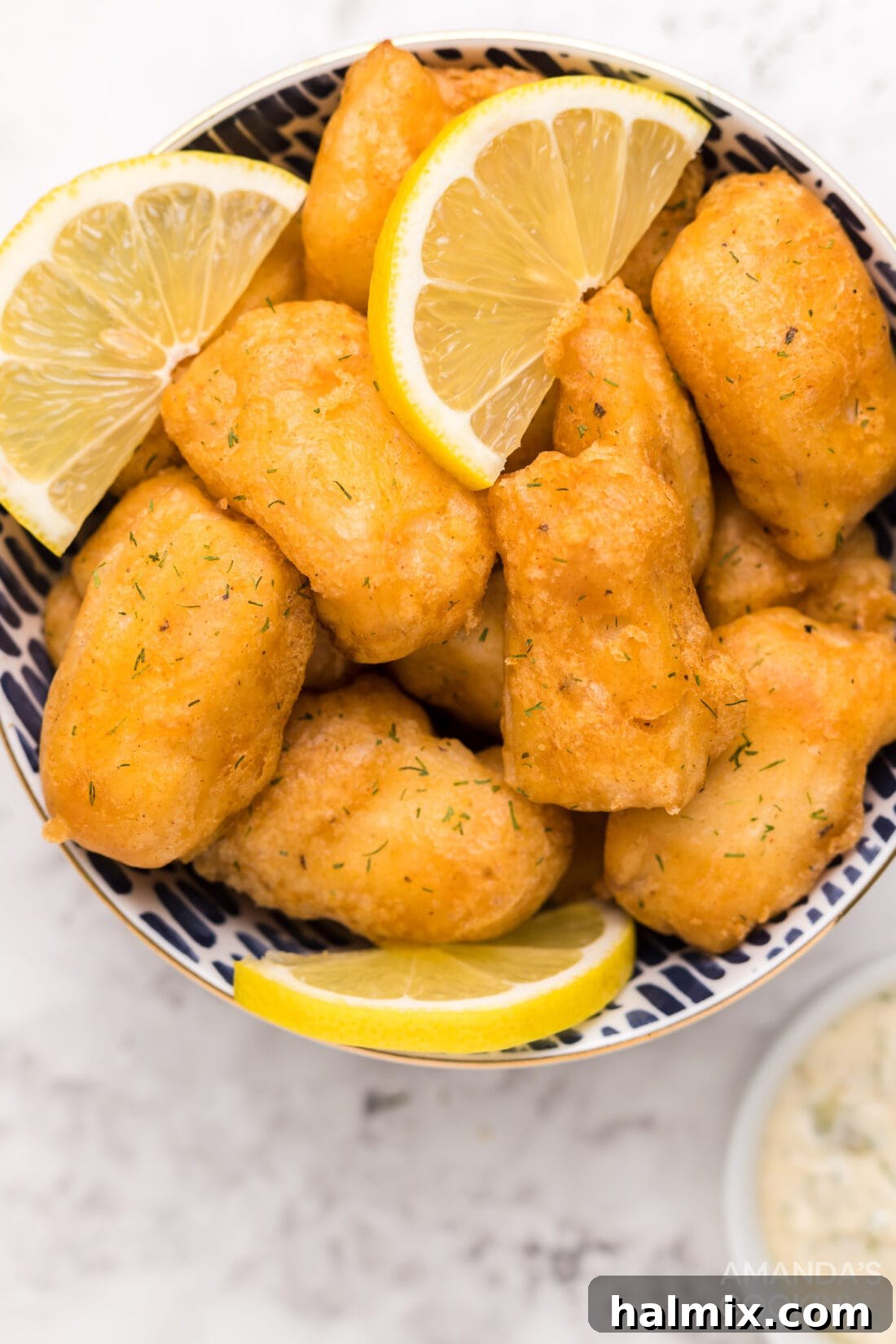 Close-up of perfectly cooked beer battered fish in a bowl, showcasing its golden, crispy texture.