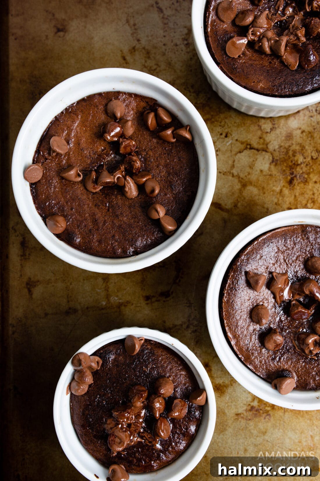 Multiple servings of unbaked air fryer brownie batter in ramekins, neatly arranged on a baking sheet, ready for the air fryer.