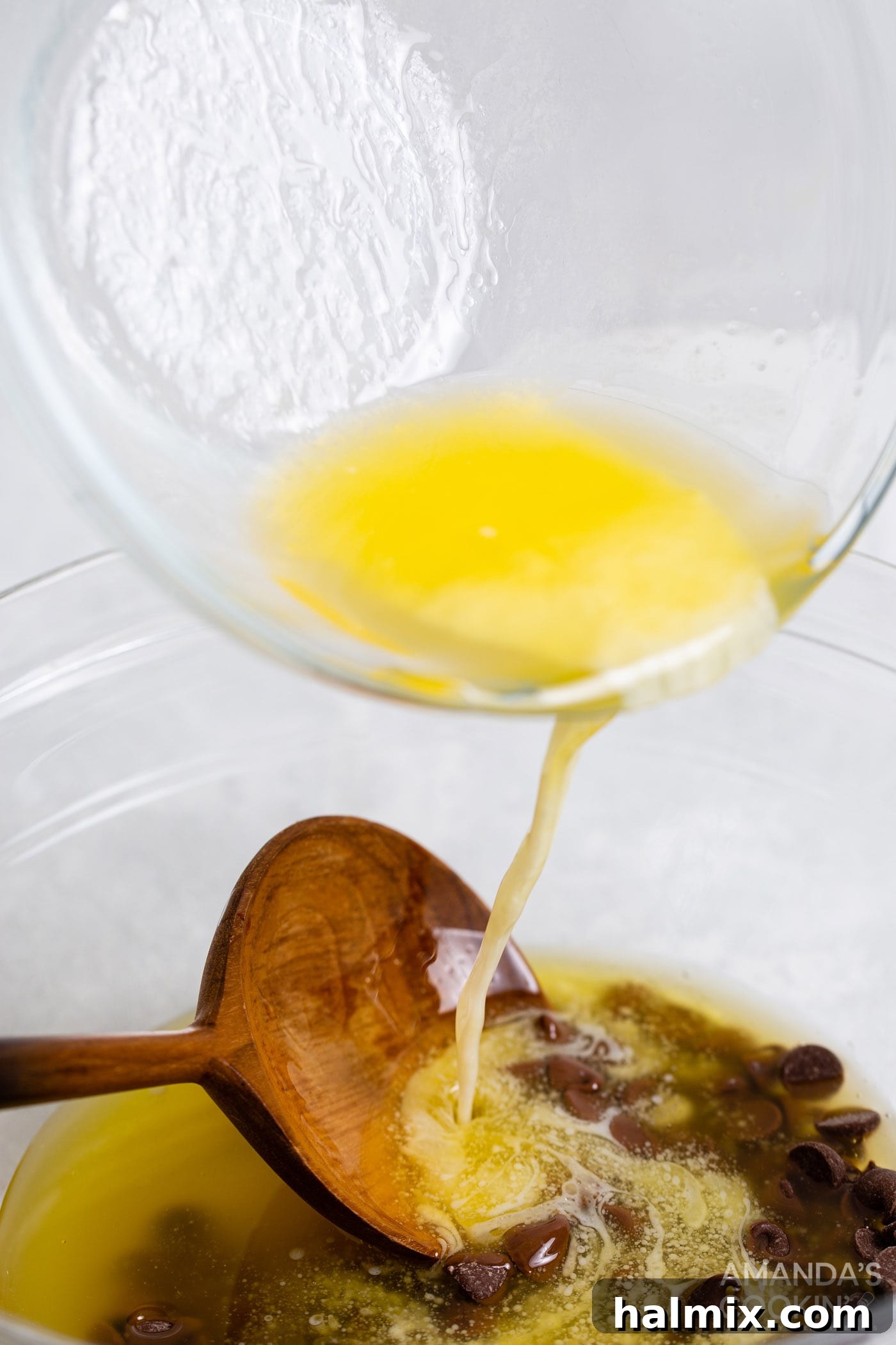 Melted butter being poured over a bowl of semi-sweet chocolate chips, starting the brownie base.