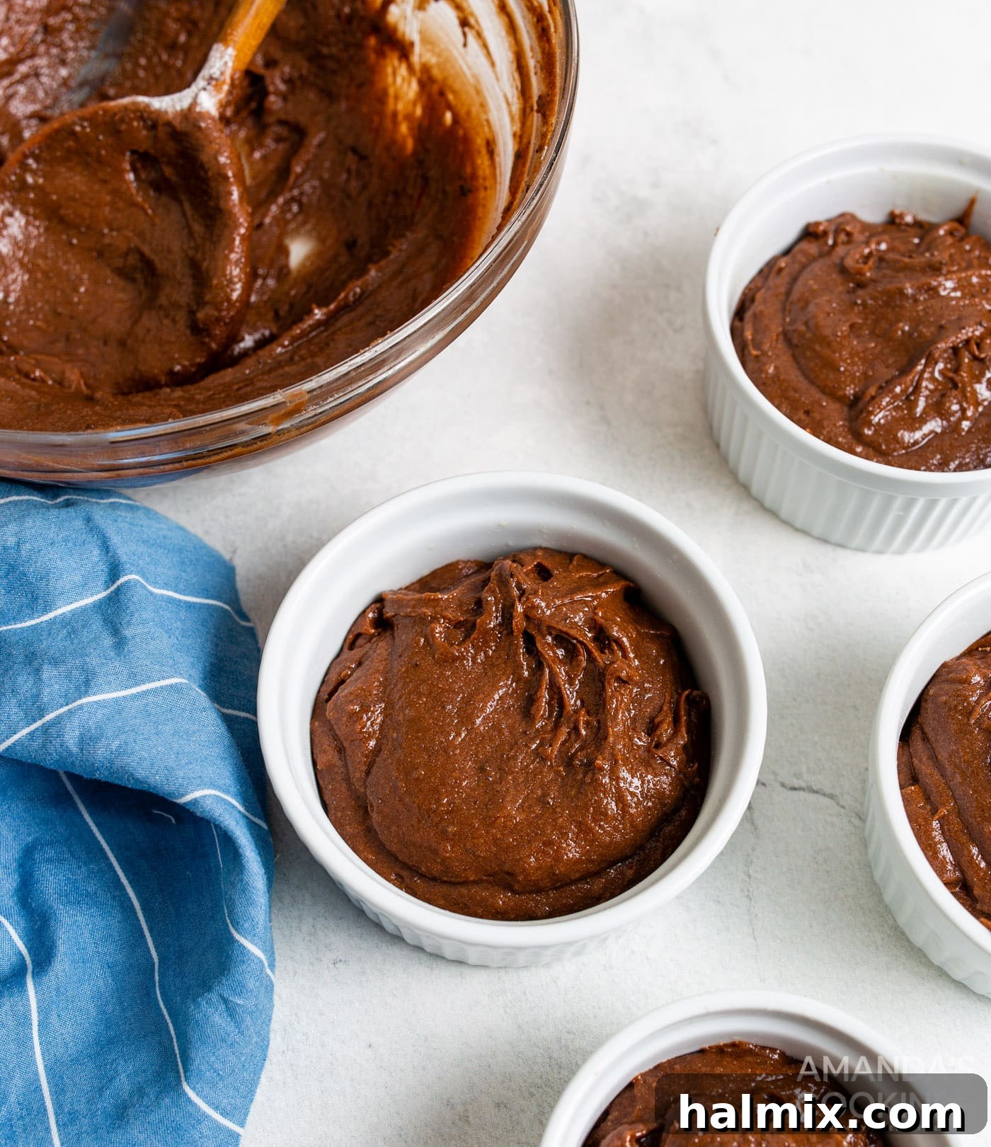 Brownie batter neatly scooped into five individual ramekins, prepared for air frying.