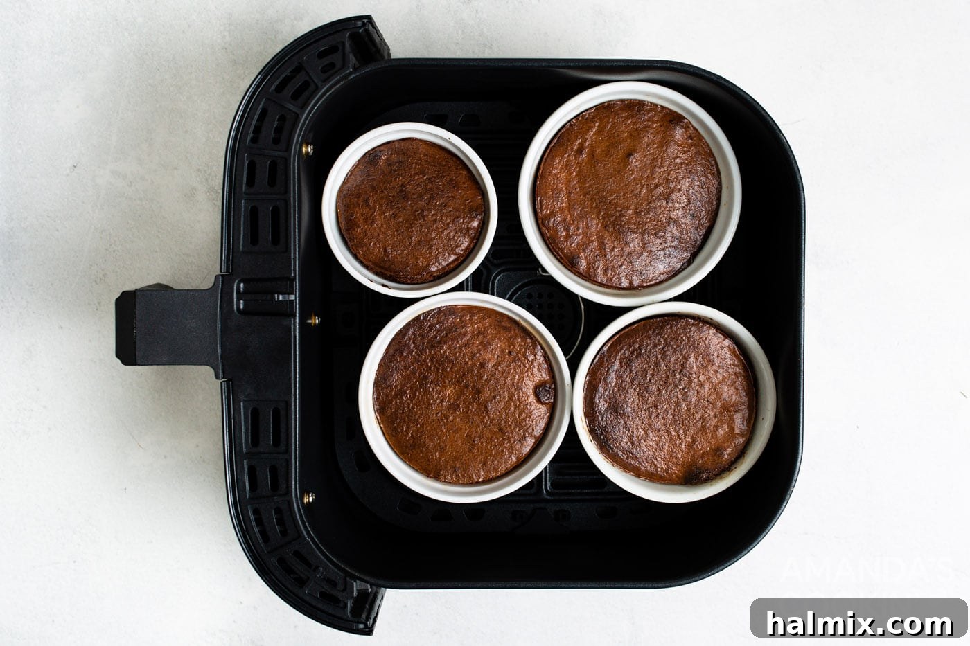 Brownie-filled ramekins baking inside an air fryer, achieving perfect individual portions.